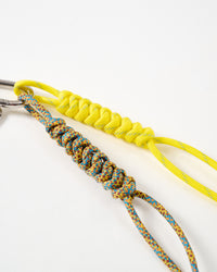 Hand-braided paracord ropes | Close-up of neon yellow and multicolor turquoise-brown hand-knotted paracord ropes with intricate braiding pattern connected to stainless steel clasp