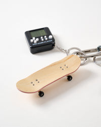 Fingerboard underside detail | Real wood fingerboard skateboard showing natural maple underside with metal trucks and black wheels alongside black Mini Game Player retro console