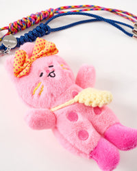 Plush bunny with knit bag | Close-up of pink handmade plush bunny with embroidered face, polka-dot bow, yellow knit crossbody bag, pink buttons, and STICKYZOO engraved tag with navy and rainbow braided ropes