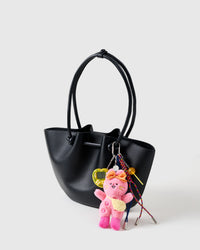 Clips onto any bag | Poppy Stack Charm on black structured tote showing pink plush bunny with bow, yellow arcade game, candy lollipop, and navy and rainbow braided ropes