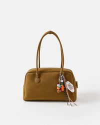 Lucky Harvest Stack Charm on olive green handbag showing carrot figure, Bee Kind tag, dice, and dark green and peach braided paracord ropes with metal tips