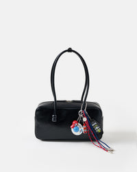 UFO Odyssey Stack Charm on glossy black shoulder bag showing flying saucer, rocket pilot figure, red cap, Keys to the UFO tag, and red and blue braided paracord ropes