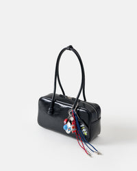 UFO Odyssey Stack Charm on black shoulder bag from three-quarter angle showing all charms including flying saucer, rocket pilot, UFO tag, and red and blue braided ropes