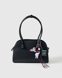 Galactic Explorer Stack Charm on black handbag showing astronaut figure, silver rocket, 3D astronaut pop-up book, and red and navy braided paracord ropes