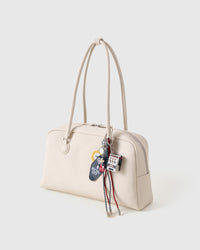 Lucky Slot Stack Charm on cream shoulder bag from side angle, all collectible pieces visible including mini slot machine and character figure with red and black paracord ropes