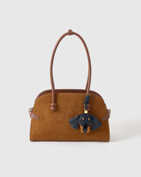 Handmade Dachshund leather bag charm shown on a tan suede handbag — hand-layered black and tan French Alran goatskin panels. STICKYZOO leather edition.