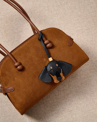 Close-up of handmade Dachshund leather bag charm — full-grain French Alran goatskin, hand-stitched edges, 18K gold-plated cube hardware. STICKYZOO leather edition.
