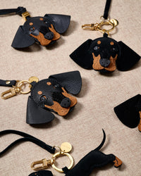 Dash Dachshund bag charm — leather edition shown alongside the suede edition variant, both handmade from French Alran goatskin. STICKYZOO Amsterdam design.