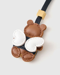 Honeybuzz Bear on a soft-yellow bag, side angle — loved by thousands of charm collectors. Real French leather, 3 days by hand.