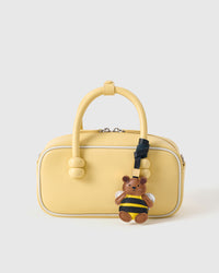 Honeybuzz Bear styled on a soft-yellow box bag, front — a small, specific piece that makes a simple bag feel joyful.