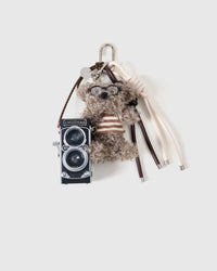 Handmade grey plush poodle bag charm with a striped sweater, sculpted glasses and a real working mini camera by STICKYZOO