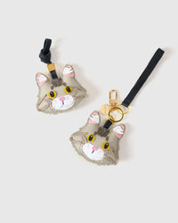 Both editions of the silver Maine Coon side by side — leather strap loop for bags, or gold-plated keychain clip.