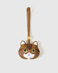 Exotic Shorthair cat charm handmade from French Alran genuine goatskin — warm caramel body, dark tabby forehead markings, amber eyes, white chin, pink nose, tan leather strap. Three days by hand. Arrives in luxury gift packaging. Designed in Amsterdam.