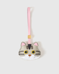 Silver-tabby British Shorthair cat charm handmade from French Alran genuine goatskin — silver-grey body, tabby stripes, pink inner ears, yellow eyes, pink leather strap. Three days by hand. Arrives in luxury gift packaging. Designed in Amsterdam.