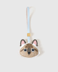 Point-Color Ragdoll cat charm handmade from French Alran genuine goatskin — cream body, dark fawn point-color ears, vivid blue eyes, dark nose, soft pink-and-blue leather strap. Three days by hand. Arrives in luxury gift packaging. Designed in Amsterdam.