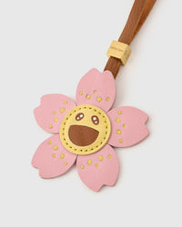 STICKYZOO Bloomy Sakura Charm clipped to a handbag — handmade French Alran goatskin in soft pink and golden yellow. 3-day artisan build.