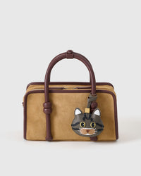 Gray-olive American Shorthair styled on a tan suede top-handle bag, front — real French leather, made to be carried on the bag that sees every day.