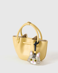 Silver Maine Coon charm styled on a soft-yellow bucket bag, side angle — 5,000+ reviews across STICKYZOO. Real French leather + suede, 3 days by hand.