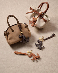 Close-up of handmade Basset Hound leather bag charm — minimalist Basset silhouette hand-cut from French Alran goatskin. STICKYZOO 3-day build.