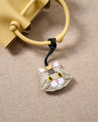 Close-up of the silver Maine Coon hanging on a yellow bag — genuine French Alran goatskin and French suede. Never faux. Never vegan.