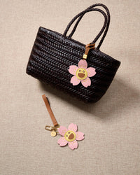Close-up of STICKYZOO Bloomy Sakura Charm — full-grain French Alran goatskin from Tarn, France. Five sakura petals with smiley face centre. 3-day handmade piece.