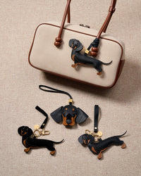 Full-body Dachshund bag charm — handmade from full-grain French Alran goatskin, hand-stitched edges, 18K gold-plated hardware. STICKYZOO Long Dash silhouette.
