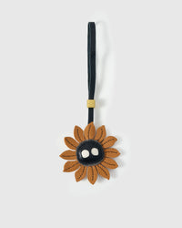 STICKYZOO Sunflower Mood Charm — caramel French Alran goatskin petals with dark centre and white dot eyes, 18K gold-plated hardware. 3-day handmade piece.