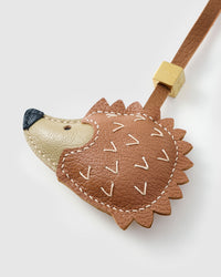 Both editions of the hedgehog charm — leather strap loop for bags, or 18K gold-plated keychain clip.