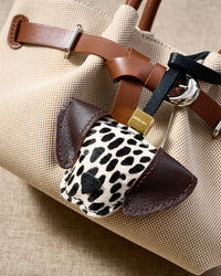 Close-up of handmade Dalmatian Spot leather bag charm — hand-stitched visible edges on French Alran goatskin, 18K gold-plated cube hardware. STICKYZOO.