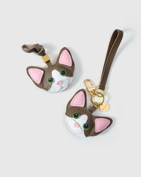 Both editions of the taupe Devon Rex side by side — leather strap loop for bags, or 18K gold-plated keychain clip with engraved disc.