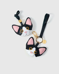 Black-and-white Devon Rex cat charm styled on a bag — real French leather, 3 days by hand.