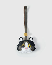 Black Ragdoll cat charm handmade from French Alran genuine goatskin — black body, grey forehead, white face mask, gold eyes, pink nose, olive-grey leather strap. Three days by hand. Arrives in luxury gift packaging. Designed in Amsterdam.