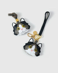 Both editions of the Black Ragdoll side by side — leather strap loop for bags, or 18K gold-plated keychain clip.