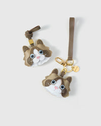 Both editions of the Classic Ragdoll side by side — leather strap loop for bags, or 18K gold-plated keychain clip.