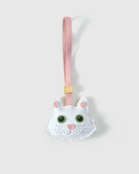 White Maine Coon cat charm handmade from French Alran genuine goatskin — pure ivory-white body, pink inner ears, large green eyes, pink heart nose, soft pink leather strap. Three days by hand. Arrives in luxury gift packaging. Designed in Amsterdam.