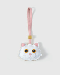 Orange-eye white Maine Coon cat charm handmade from French Alran genuine goatskin — pure ivory body, pink inner ears, vivid orange eyes, pink heart nose, soft pink leather strap. Three days by hand. Arrives in luxury gift packaging. Designed in Amsterdam.