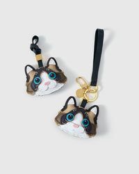 Both editions of the Ragdoll side by side — leather strap loop for bags, or 18K gold-plated keychain clip with engraved STICKYZOO disc.
