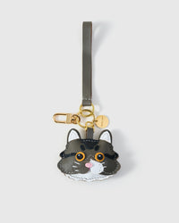 Long-hair tabby cat charm in both leather strap and 18K gold-plated keychain editions — strap loop for bags, or clip for keys.