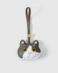 Grey Muse British Shorthair charm — grey face with white face mask, gold eyes, pink inner ears, pink nose, olive-grey leather strap. Hand-cut from real French Alran goatskin over three days.