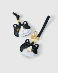 Both Black Muse editions of the British Shorthair side by side — leather strap loop for bags, or 18K gold-plated keychain clip.