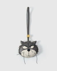 The Grump cat charm handmade from French Alran genuine goatskin — grey body, dark masked eye markings, white muzzle, gold-orange eyes, real fiber whiskers, grey leather strap. Three days by hand. Arrives in luxury gift packaging. Designed in Amsterdam.