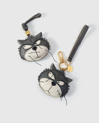 Both editions of the Grump cat side by side — leather strap loop for bags, or 18K gold-plated keychain clip with engraved disc.