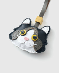 Tight close-up of the Black Ragdoll face, angled — gold eyes in real leather, grey forehead markings, white face mask, pink nose. Every panel by hand.