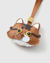 Tight close-up of the orange long-hair tabby — every brown tabby stripe hand-stitched into the caramel French Alran leather, gold-yellow eyes layered in real leather.