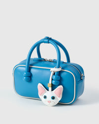 Snow-white Devon Rex cat charm in strap and keychain editions — real French leather, finished one at a time by hand.