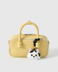 Dragon Li styled on a soft-yellow box bag, front — a small, specific piece that turns a simple bag into a personal one.
