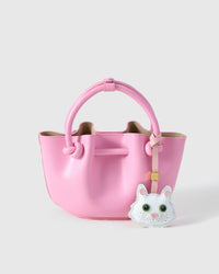 White Maine Coon charm styled on a soft pink bucket bag, front — a small, specific piece that turns a simple bag into a personal one.