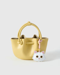 Orange-eye Maine Coon styled on a soft-yellow bucket bag, front — a small, specific piece that turns a simple bag into a personal one.
