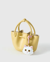 Orange-eye Maine Coon styled on a soft-yellow bucket bag, side angle — real French leather, 3 days by hand.