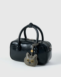 Blue British Shorthair on a glossy black box bag, side angle — Real French leather, 3 days by hand.